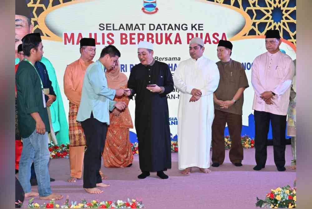 Hajiji (empat dari kanan) menyampaikan sumbangan kepada asnaf pada Majlis Berbuka Puasa bersama Ketua Menteri di pekarangan Masjid An-Nur, Tuaran.