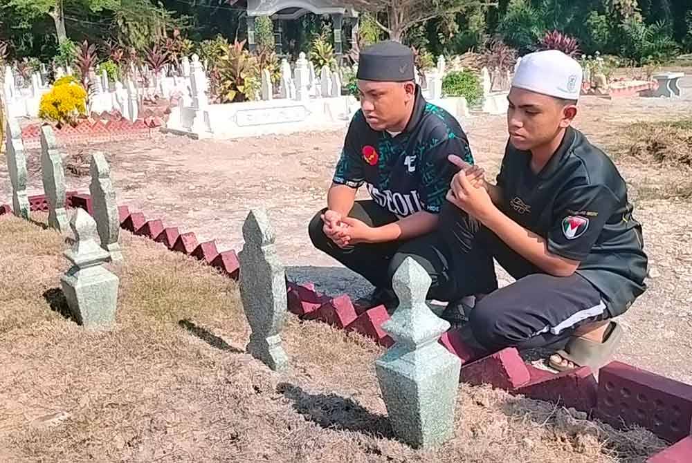 Abdur Rahman (kiri) dan Abdullah membaca doa di pusara ayah, ibu dan adik beradik di tanah perkuburan Islam Masjid Jamek Ubuddiah Parit Limbong Muar.