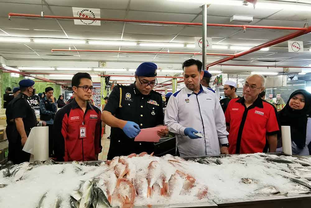 Saharuddin (tiga dari kanan) memantau harga ikan yang ditawarkan di pasar raya runcit, Sabasun HypeRuncit di Bukit Kecil, Kuala Terengganu.