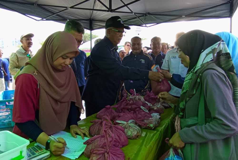 Mahfuz (tiga dari kiri) melayan pengunjung yang hadir ke program Jualan Agro Madani Mega Raya di Dataran Jalan Istana Lama, di sini, pada Sabtu.