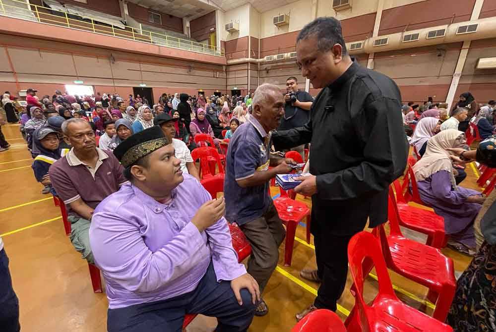 Reezal (kanan) menyampaikan sumbangan kepada 400 anak yatim dan asnaf menerusi Majlis Kasih Ramadan, Ceria Aidilfitri Peringkat Kepala Batas, di Kompleks Sukan MBSP pada Sabtu.