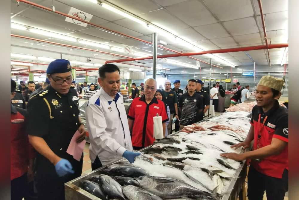 Shaharuddin (dua dari kiri) meninjau bekalan ikan yang dijual di pasar raya SabasunHyperRuncit di Kuala Terengganu.