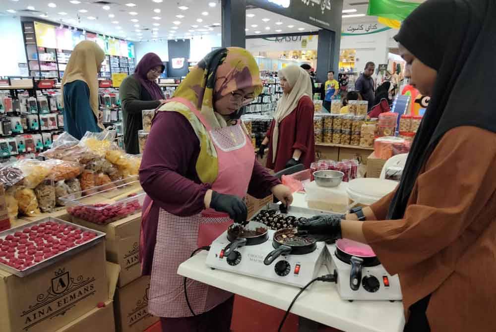 Nor Aina (kiri) bersama pembantunya membakar biskut secara segar di ruang legar sebuah pasar raya.