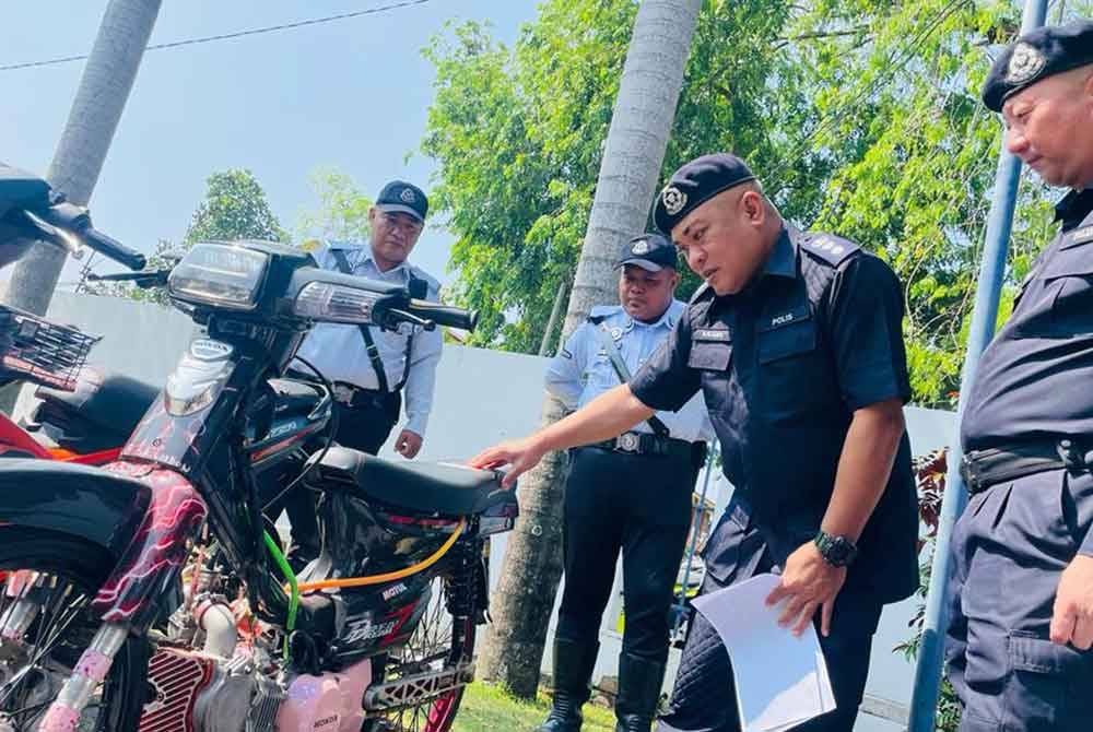 Abang Zainal Abidin (dua dari kanan) menunjukkan sebuah motosikal yang disita selepas didapati diubah suai pemiliknya dalam Op Bersepadu Samseng Jalanan di Ipoh.