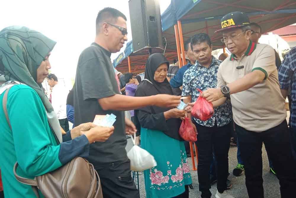 Jalaluddin (kanan) ketika menyantuni pengunjung yang datang dalam program berkenaan.