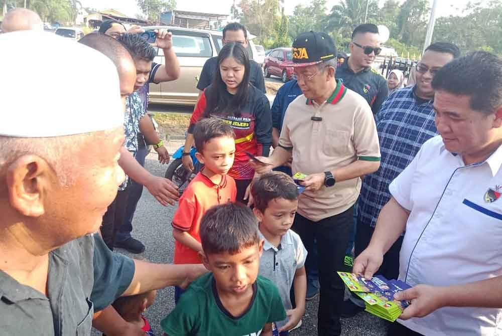 Jalaluddin (dua kanan) berkesempatan menyampaikan duit raya kepada kanak-kanak pada program itu.