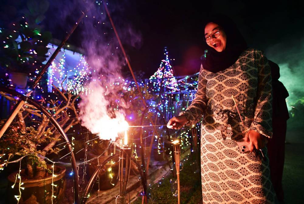 Seorang remaja menyalakan bunga api menggunakan lampu pelita minyak tanah bagi memeriahkan lagi suasana bagi pertandingan bertuntung. Foto Bernama