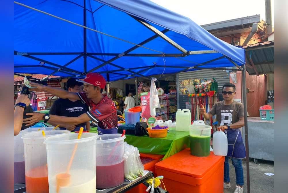 Muhamad Hamdan (kanan) menyediakan air balang untuk dijual di bazar Ramadan Felda Gunung Besout 1, Sungkai.