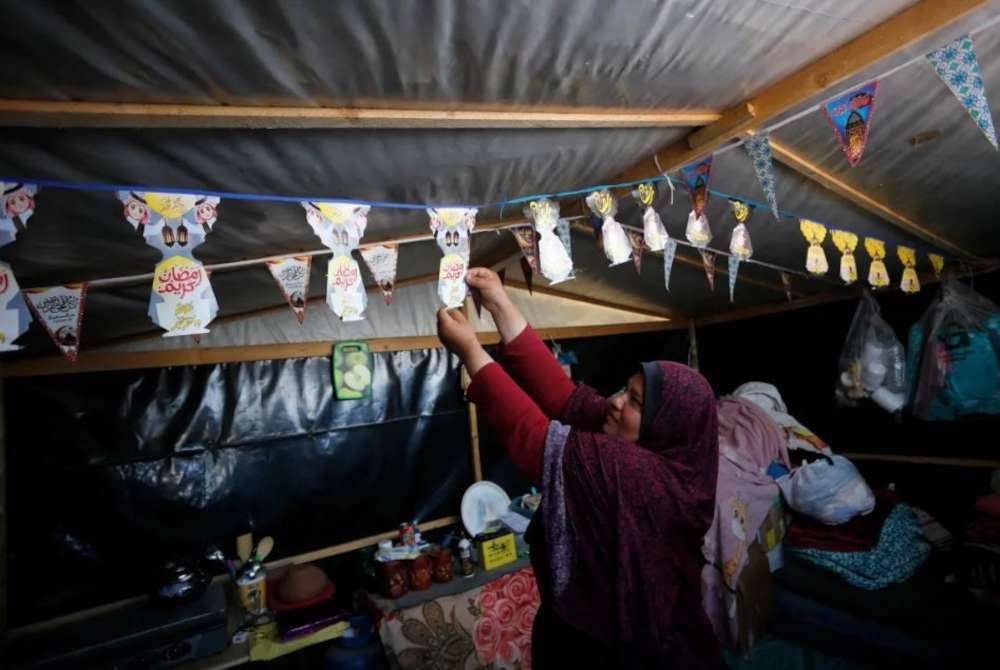 Seorang wanita menghias khemah keluarganya di Deir el-Balah di Bandar Gaza. Foto AFP