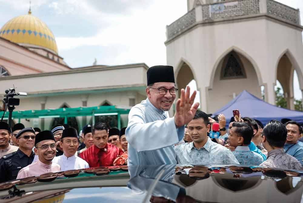 Anwar melambai tangan selepas menunaikan solat Jumaat bersama rakyat di Masjid Bandar Utama Batang Kali hari ini. Foto Bernama