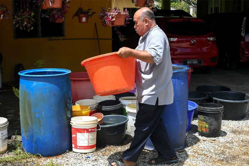 Saufi Ariffin, 60, mengagihkan air ke dalam bekas simpanan untuk kegunaan keluarganya berikutan gangguan bekalan air ketika ditemui Bernama di Kampung Chengal Pulas pada Jumaat. Foto Bernama