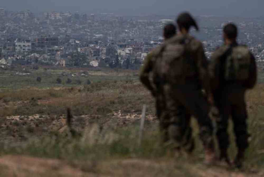 Anggota tentera rejim Zionis Israel melihat bangunan yang musnah di Semenanjung Gaza. Foto AP