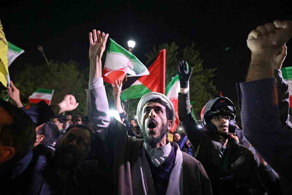 Rakyat Iran mengibarkan bendera Palestin berkumpul di hadapan kedutaan Britain di Teheran selepas Iran melancarkan serangan dron di wilayah Israel. Foto AFP