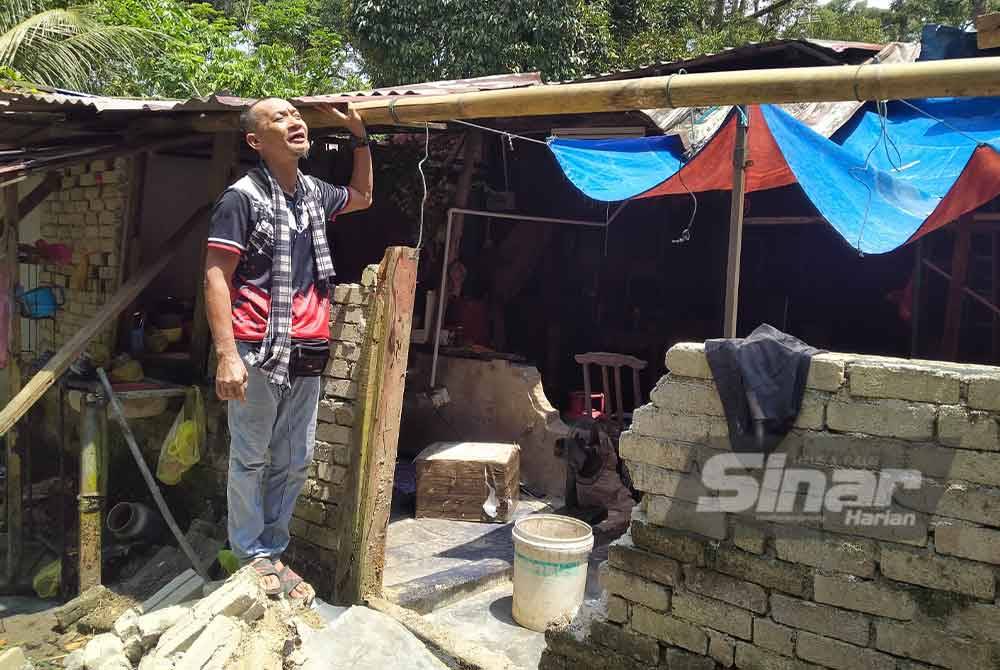 Baderol Hisam menunjukkan keadaan bahagian dapur rumahnya yang ditimpa pokok kelapa sawit ketika ditemui di rumahnya di Kampung Sungai Lubok, Trong pada Ahad.