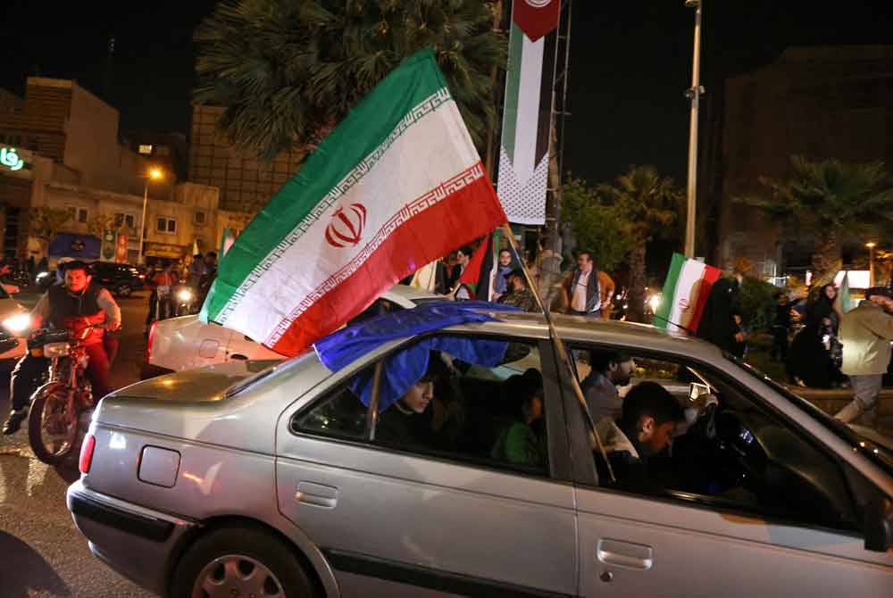 Penduduk Iran berarak sambil mengibarkan bendera kebangsaan menuju ke Dataran Palestin di ibu kota sebagai meraikan serangan balas terhadap Israel. - Foto AFP