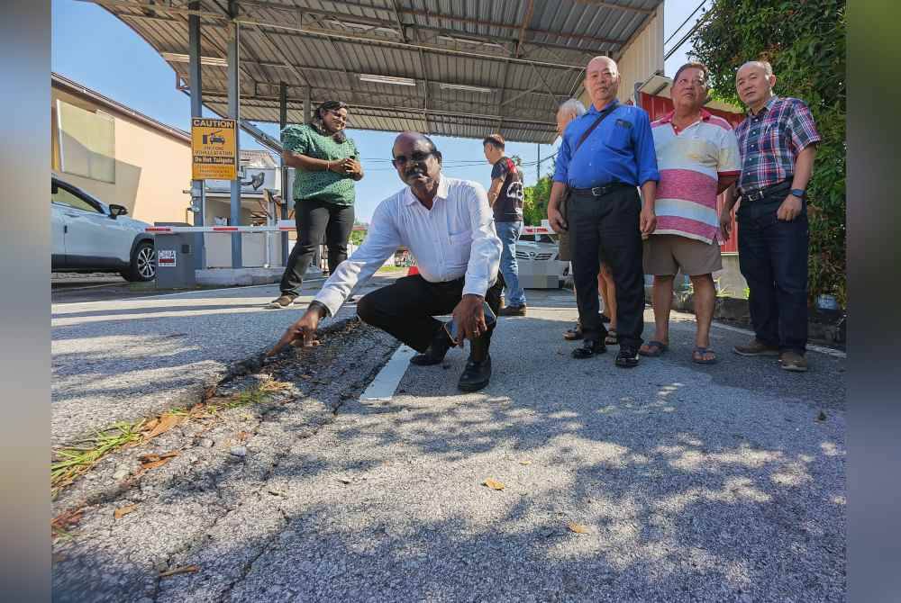 Gunasekaran (dua dari kiri) menunjukkan keadaan jalan masuk Taman Sri Kamban di Seremban yang retak.