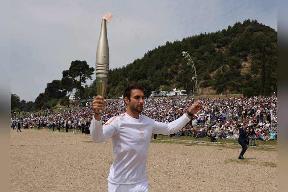 Pembawa obor pertama, pendayung Yunani, Stefanos Ntouskos membawa api semasa permulaan lari berganti-ganti selepas upacara nyalaan api untuk Sukan Olimpik Paris 2024 di Olympia Purba di Greece pada Selasa. Foto Reuters