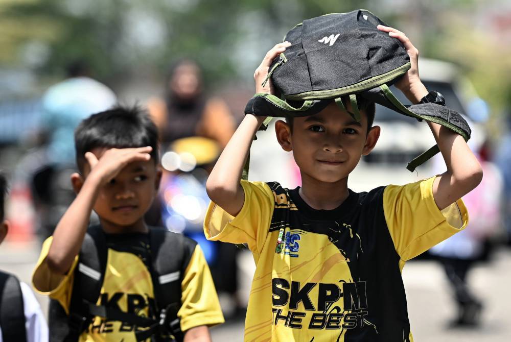 Sebahagian murid sekolah menutup kepala dengan menggunakan beg ekoran cuaca panas.