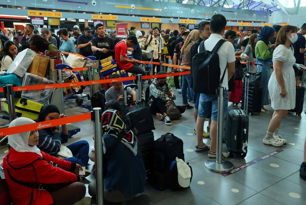 Penumpang pesawat Air Asia beratur di kaunter bagi mendapatkan info terkini dan menjadualkan semula penerbangan berikutan kesemua penerbangan dari Lapangan Terbang Antarabangsa Kuala Lumpur (KLIA) Terminal 2 ke Tawau Sabah dibatalkan berikutan letusan gunung berapi di Gunung Ruang, Indonesia. Foto Bernama