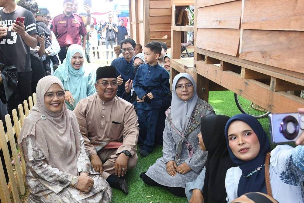 Sanusi (dua dari kiri) dan isteri, Tok Puan Jusmalailani Jusoh (kiri) bergambar bersama tetamu di halaman replika rumah kayu di Seri Mentaloon.