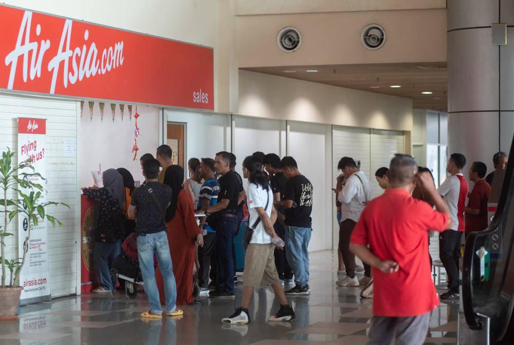 Penumpang Air Asia beratur di kaunter Lapangan Terbang Labuan untuk mendapatkan maklumat terkini dan menjadualkan semula penerbangan susulan pembatalan akibat letusan gunung berapi di Gunung Ruang, Indonesia pada Khamis. Foto Bernama