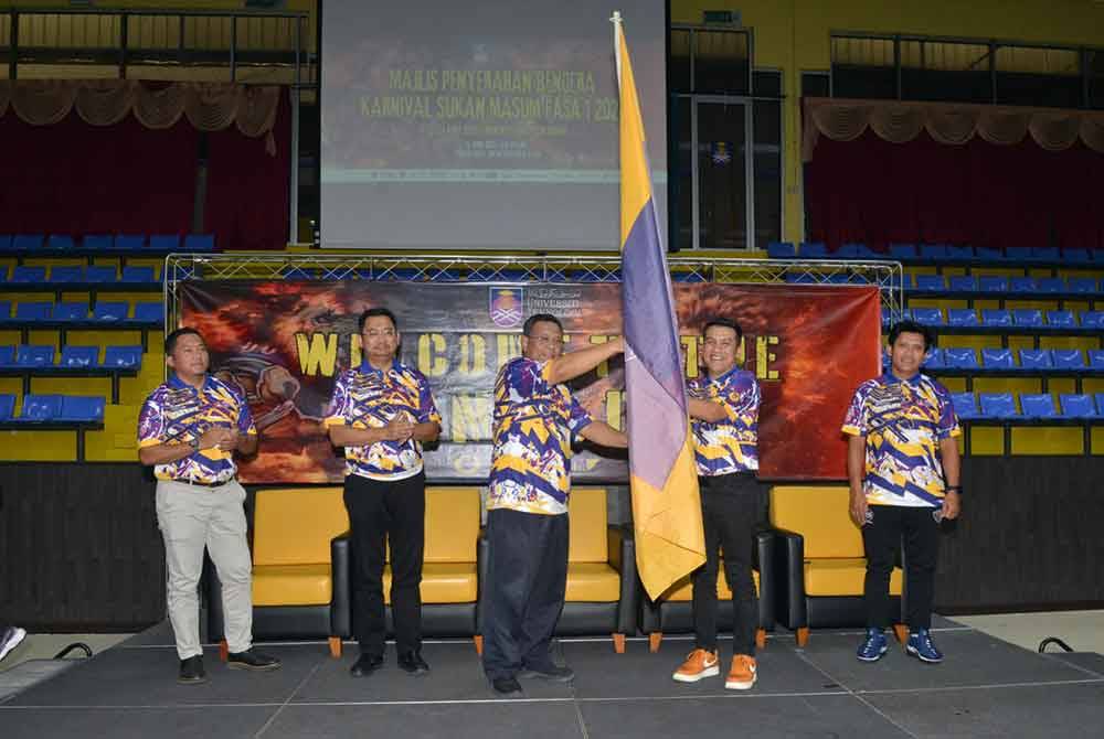 Mohd Sazili (kiri) menyerahkan bendera UiTM kepada ketua kontinjen universiti itu pada Khamis.