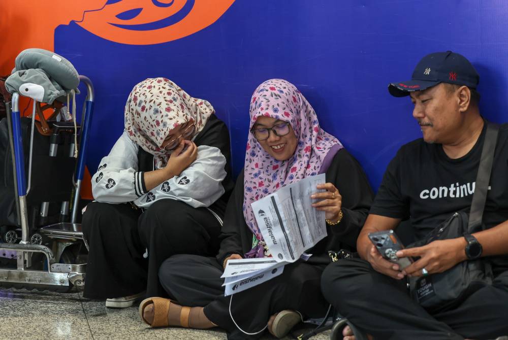 Suriani, 48, bersama suami dan anaknya melihat jadual penerbangan baharu semasa terkandas di Lapangan Terbang Antarbangsa Kuala Lumpur (KLIA) Terminal 1 hari ini berikutan letusan Gunung Ruang, Indonesia. Foto Bernama