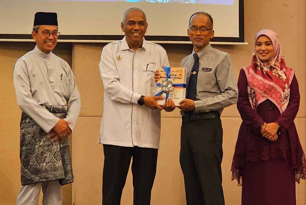 Khairudin (dua dari kiri) menyerahkan set buku tambahan kepada wakil guru pada Majlis Penyerahan Buku Tuisyen Asrama Harian negeri Perak di Ipoh.