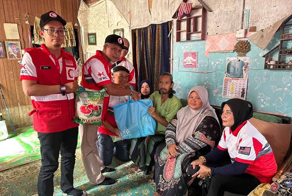 Ahmad (dua dari kiri) menyampaikan bantuan makanan kepada Mohd Azli (tiga dari kanan).