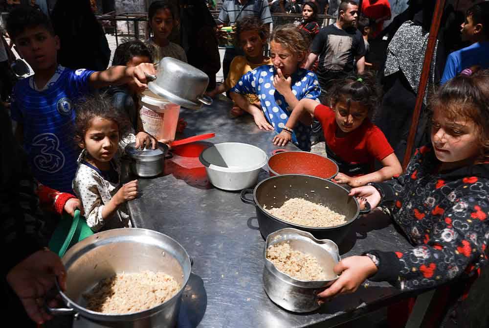 Kanak-kanak Palestin yang dipindahkan beratur untuk menerima makanan di Rafah, di selatan Semenanjung Gaza pada Jumaat. Foto AFP