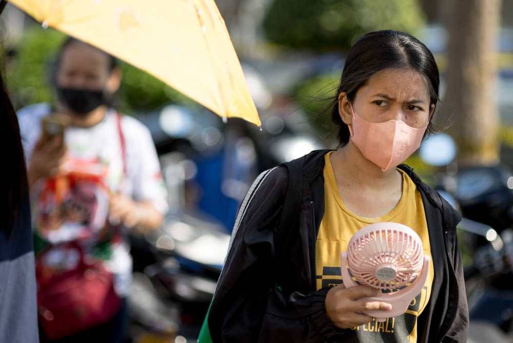 Penduduk Thailand menyejukkan badan dengan membawa kipas mudah alih semasa berjalan-jalan di Bangkok. Foto AFP