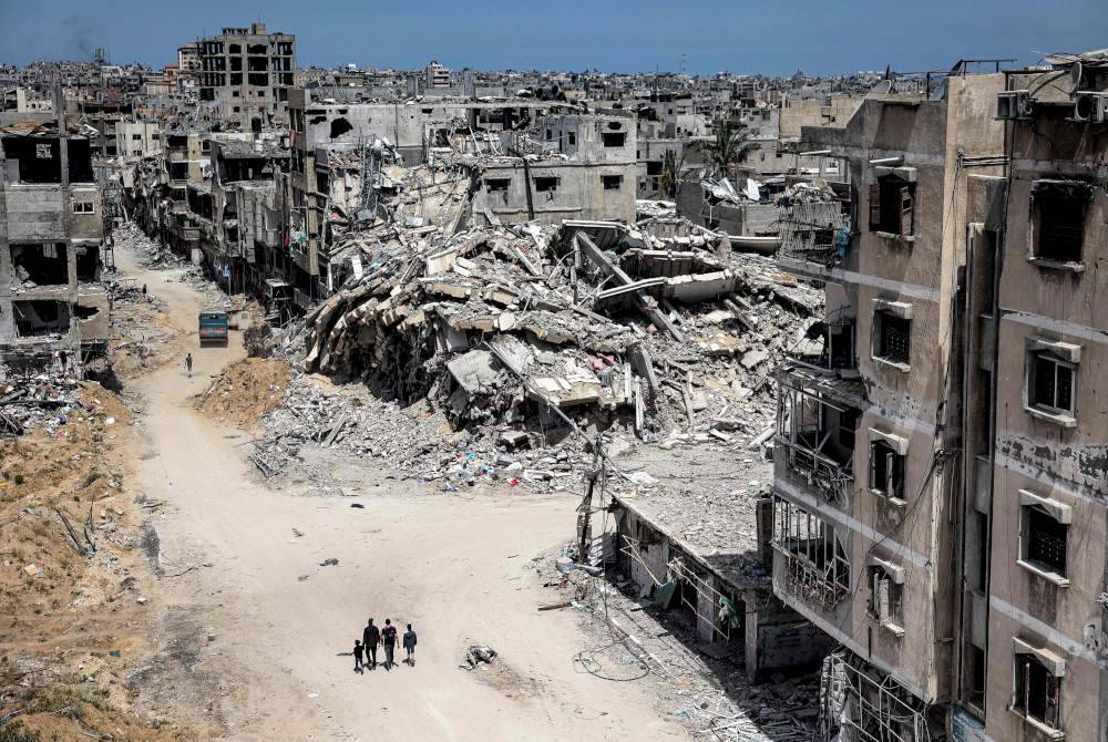 Orang ramai berjalan melepasi bangunan yang musnah di Khan Yunis di selatan Semenanjung Gaza pada Isnin di tengah-tengah konflik berterusan antara Israel dan pejuang Hamas. Foto AFP