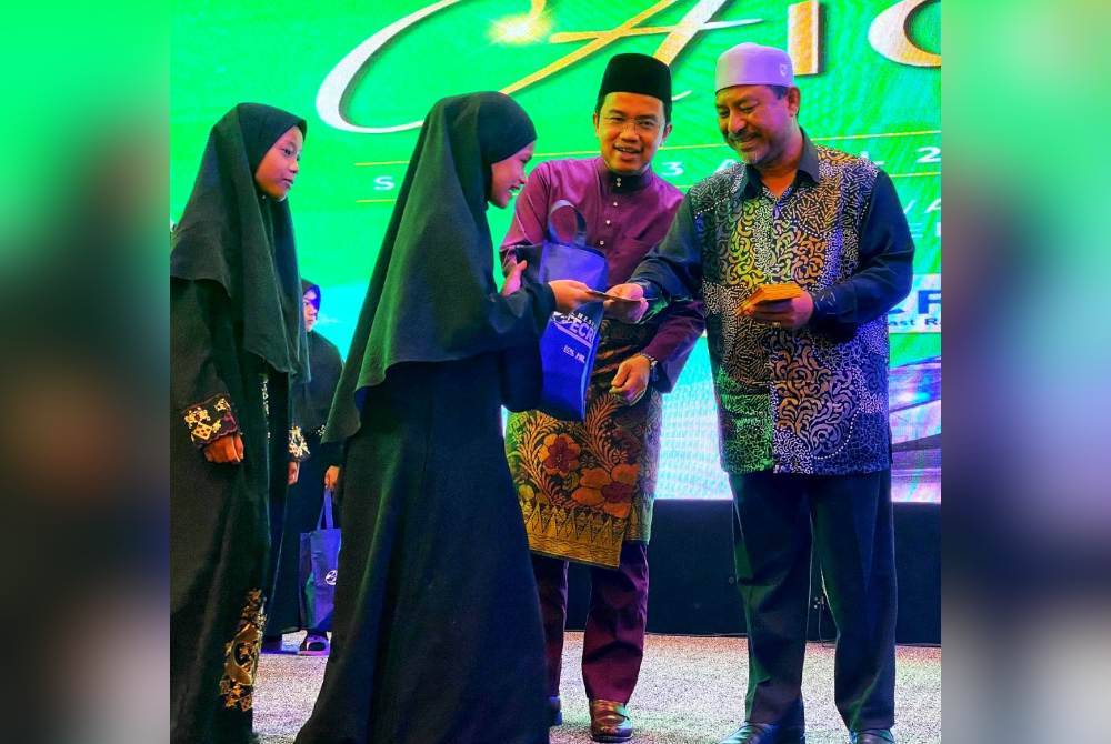 Darwis (dua dari kanan) menemani Mohd Nassuruddin (kanan) menyampaikan sumbangan kepada anak yatim pada Majlis Rumah Terbuka Aidilfitri Projek Laluan Rel Pantai Timur (ECRL) di Kota Bharu, pada Selasa.