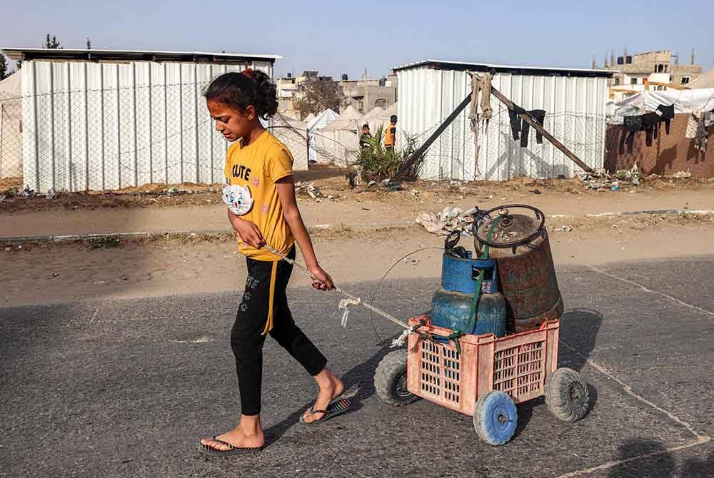 Kanak-kanak ini membawa tong gas di Rafah. (Gambar kecil: Hafidzi) Foto AFP