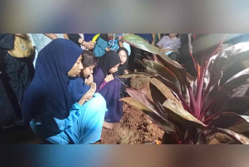 Anak Allahyarham Noor Rahiza membaca doa untuk arwah ibu tercinta di Tanah Perkuburan Islam Masjid Haji Nyak Gam, Kampung Ruat pada malam Rabu.