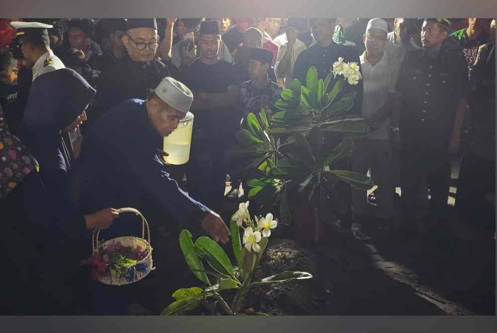 Bapa Allahyarham, Mohd Termizi Abdul Ghani, 68, menyiram air di pusara anak sulungnya selepas selesai pengebumian di Tanah Perkuburan Islam Batu 10, Lekir.