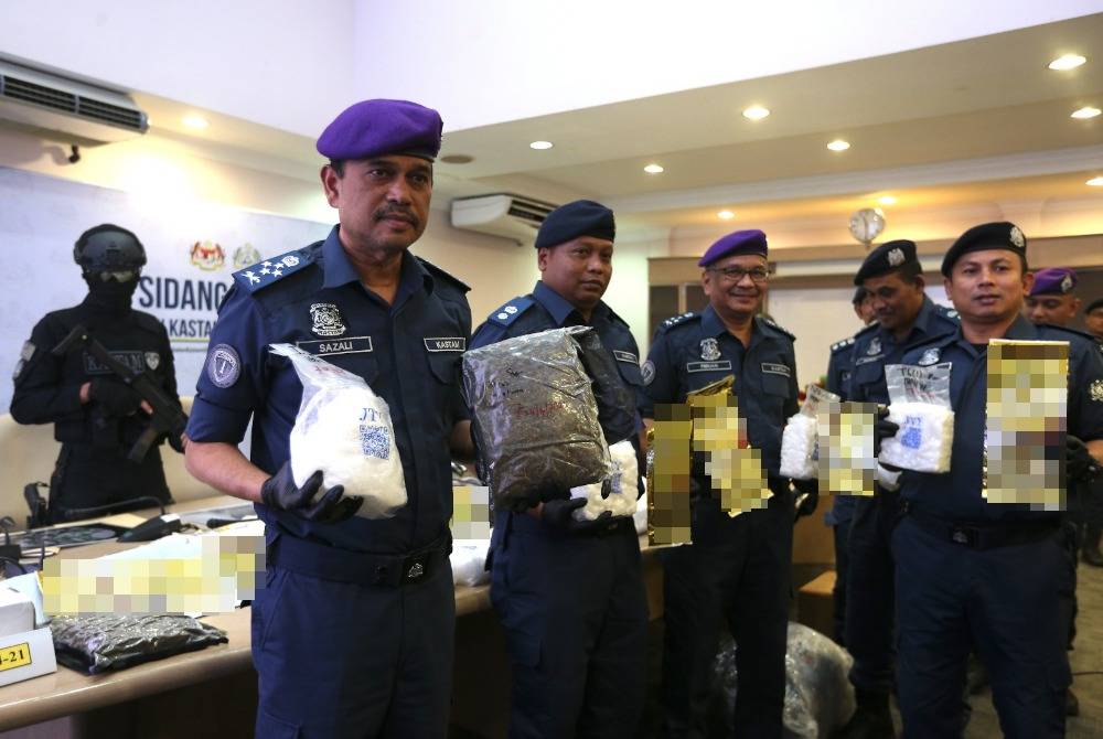 Sazali (kiri) menunjukkan bungkusan dadah yang dirampas di Cawangan Narkotik Ibu Pejabat JKDM di Kampung Jijan hari ini.