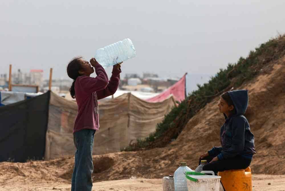 Kanak-kanak Palestin menunggu bantuan bekalan air dalam suasana cuaca panas di Rafah. Foto AFP