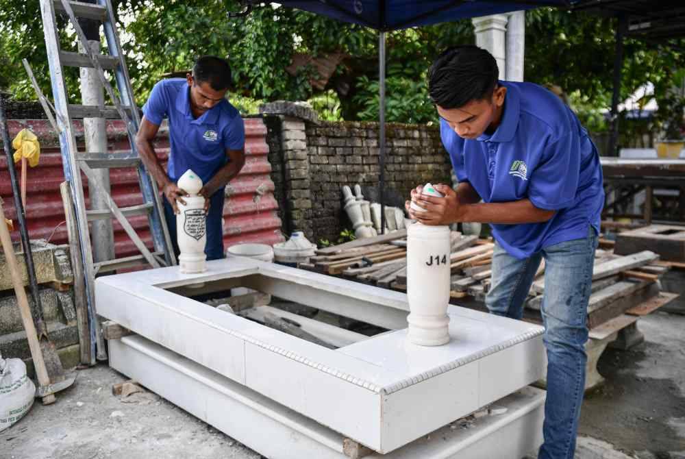 
Aiman Hakim (kanan) bersama Irwan Shah melakukan kerja-kerja memasang batu nisan pada kepok yang disiapkan mereka. Foto Bernama