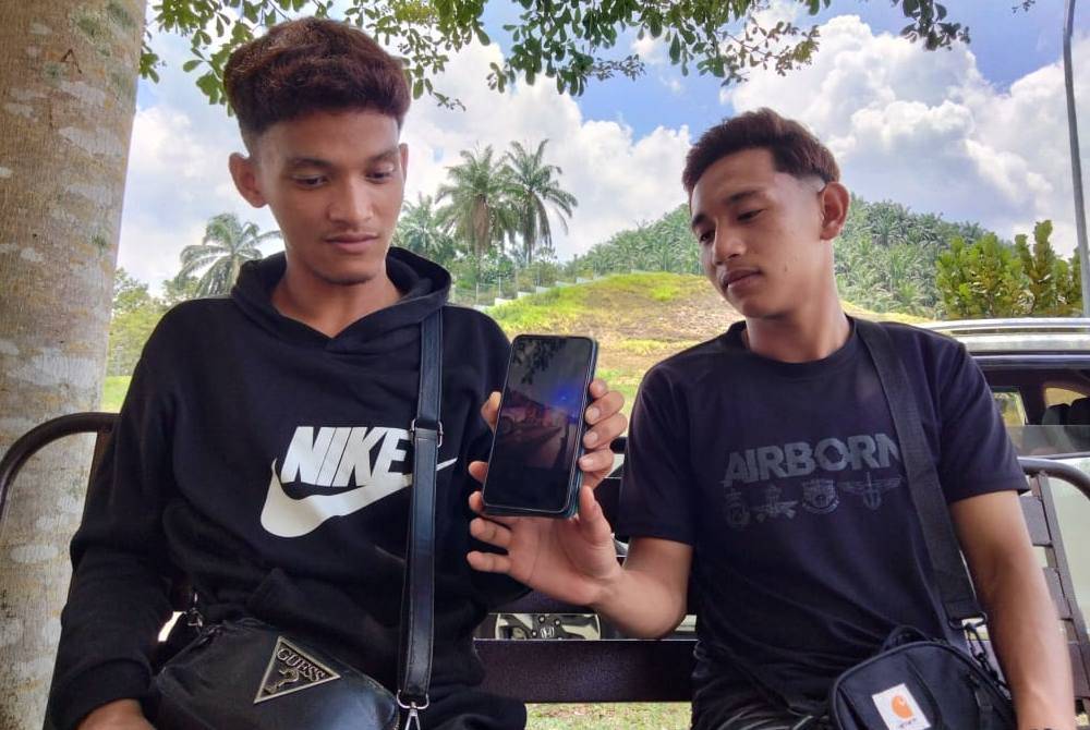 Muhammad Afiq Anaqi (kiri) menunjukkan gambar kenderaan bapanya yang terlibat kemalangan