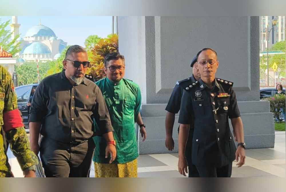 Che&#039;gu Bard (tengah) yang memakai baju Melayu berwarna hijau dibawa oleh pihak polis ke mahkamah dalam keadaan bergari.