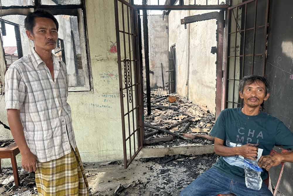 Mohd Fauzi (kanan) dan Azlizul (kiri) yang keletihan selepas berjaya menyelamatkan diri dalam kebakaran di Beris Kubur Besar di Bachok.