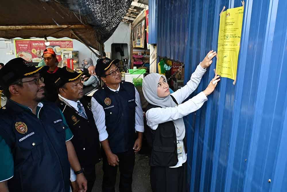 Anggota penguat kuasa Jabatan Kesihatan Negeri menampal notis penutupan terhadap salah sebuah premis yang dikesan beroperasi dalam keadaan tidak bersih.