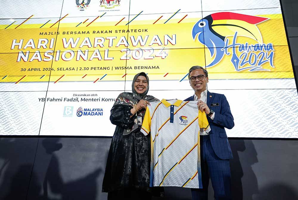 Fahmi (kanan) menerima baju sempena penganjuran Hawana 2024 yang disampaikan oleh Nur-ul Afida pada Majlis Bersama Rakan Strategik Hawana 2024 di Wisma Bernama pada Selasa. Foto Bernama