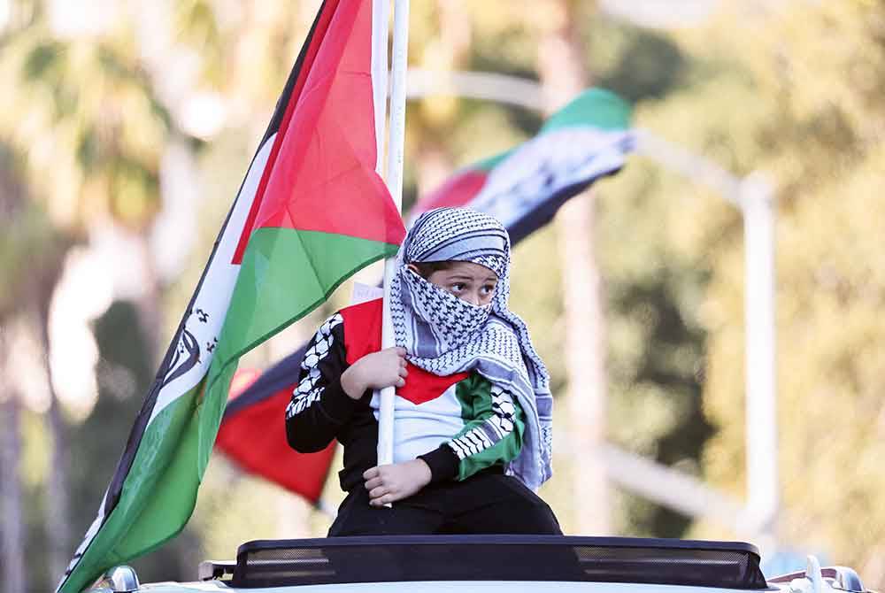 Seorang penunjuk perasaan termuda mengibarkan bendera Palestin semasa &#039;Perarakan Kanak-Kanak Demi Palestin&#039; di Los Angeles, California. - AFP