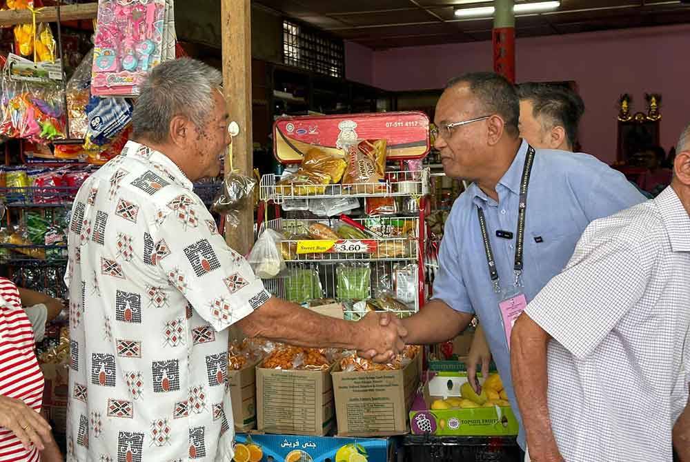 Khairul Azhari (kiri) sempat beramah mesra bersama penduduk setempat ketika berkempen di sekitar Kuala Kubu Baharu.