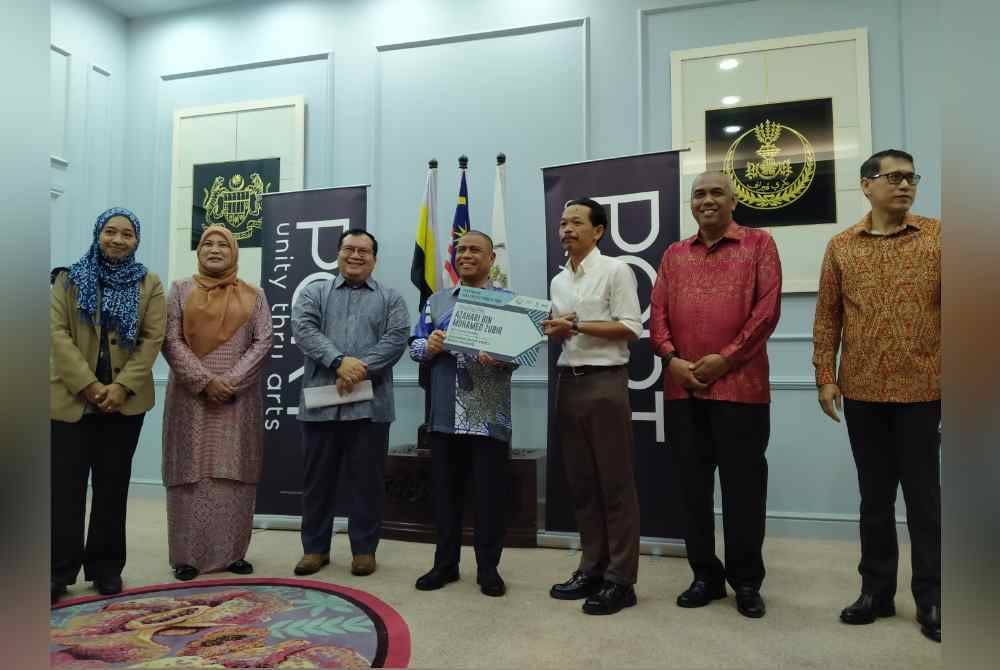 Saarani (tengah) menyampaikan replika cek kepada penerima ketika menyempurnakan Penyampaian Replika Cek Dana Kreatif Negeri Perak @ PORT di Pejabat Menteri Besar Perak di sini pada Khamis.