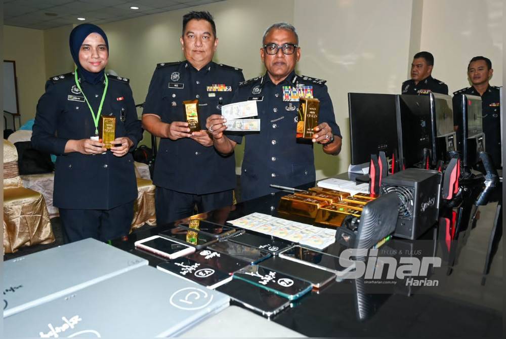 Ramli (kanan) menunjukkan replika jongkong emas dan duit palsu yang digunakan sindiket bagi menjerat mangsa.