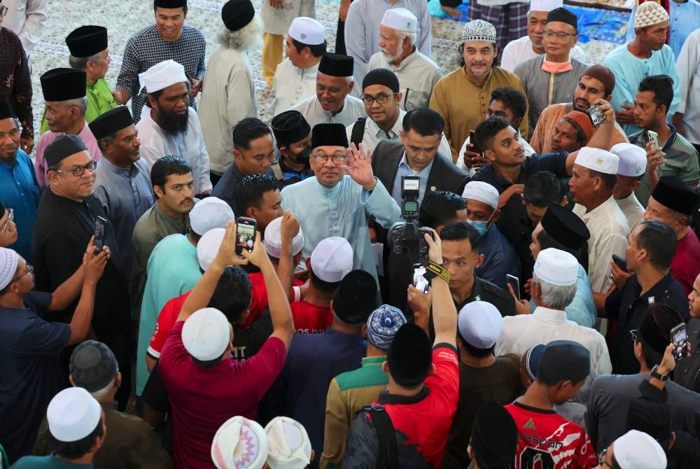 Anwar (tengah) melambaikan tangan kepada jemaah selepas menunaikan solat Jumaat bersama rakyat di Masjid Kampung Sungai Merab, Kajang hari ini. Foto Bernama