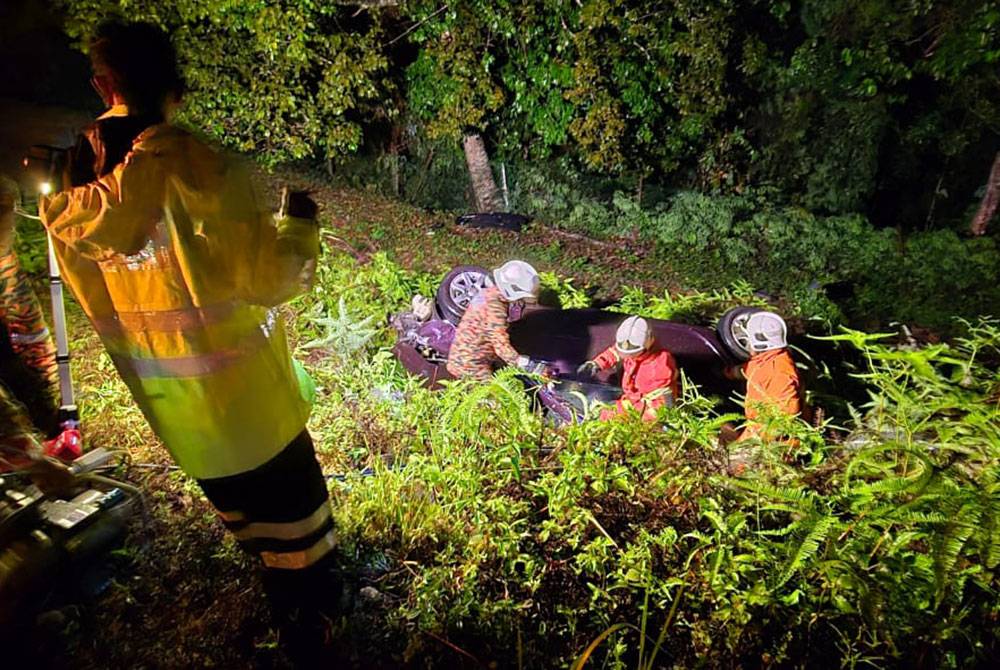 Anggota bomba membantu mengeluarkan mangsa dari kenderaan yang terbabas sebelum terjatuh ke bawah cerun di di Kilometer 212 LPT1 di sini pada tengah malam Jumaat.